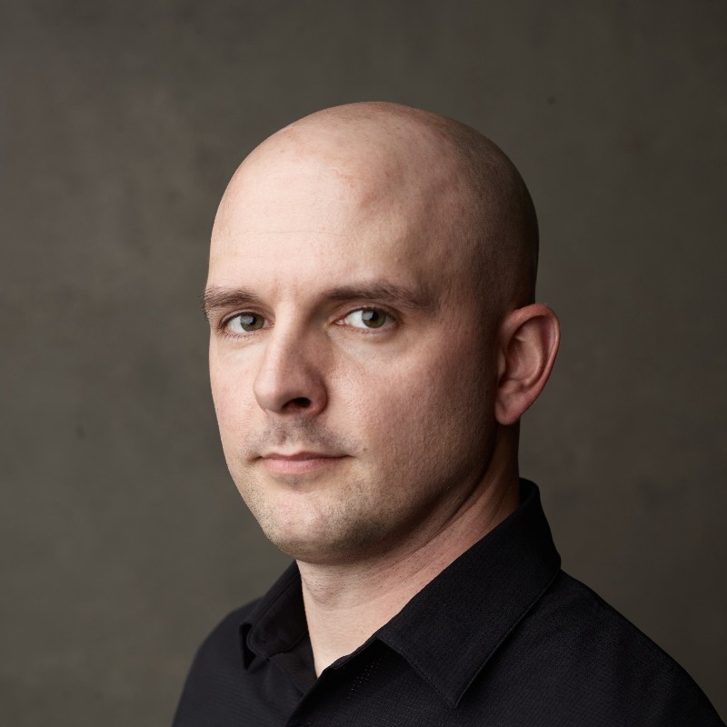 Picture of Andrew Huth, a bald guy wearing a black button-down shirt